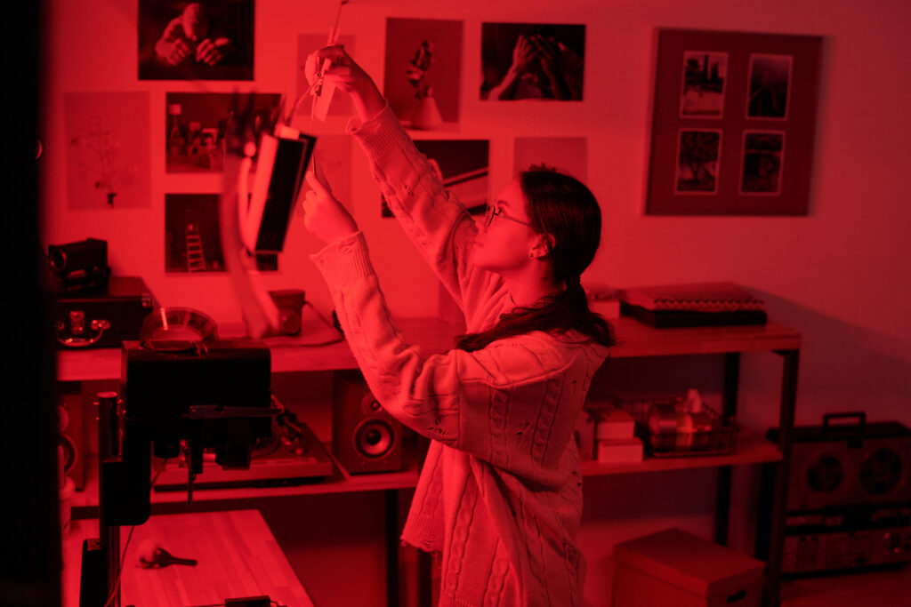 Une photographe suspend des tirages photographies argentiques pour les faire sécher dans une chambre noire