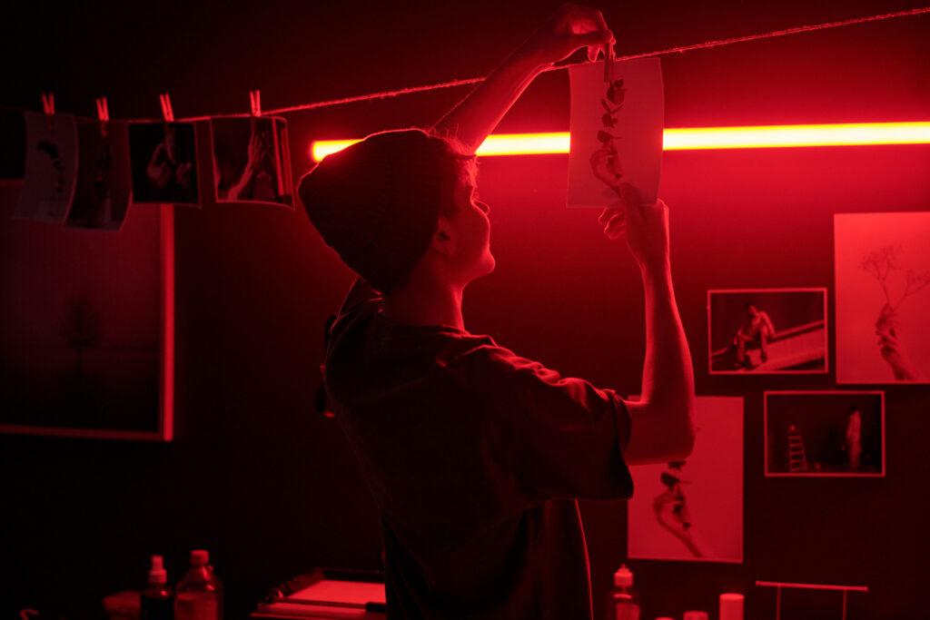 lumière rouge photographie argentique accrochant un tirage photo dans une chambre noire